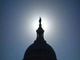 Freedom statue atop the US Capitol silhouetted against the sun 